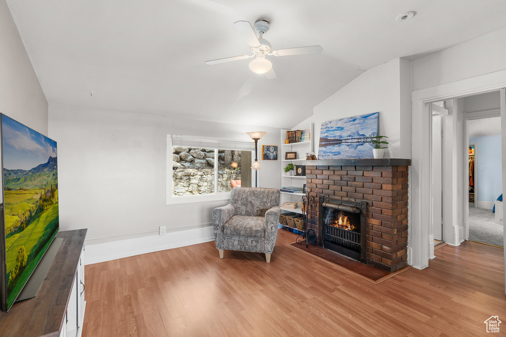 Sitting room with ceiling fan, lofted ceiling, a fireplace, and wood finished floors