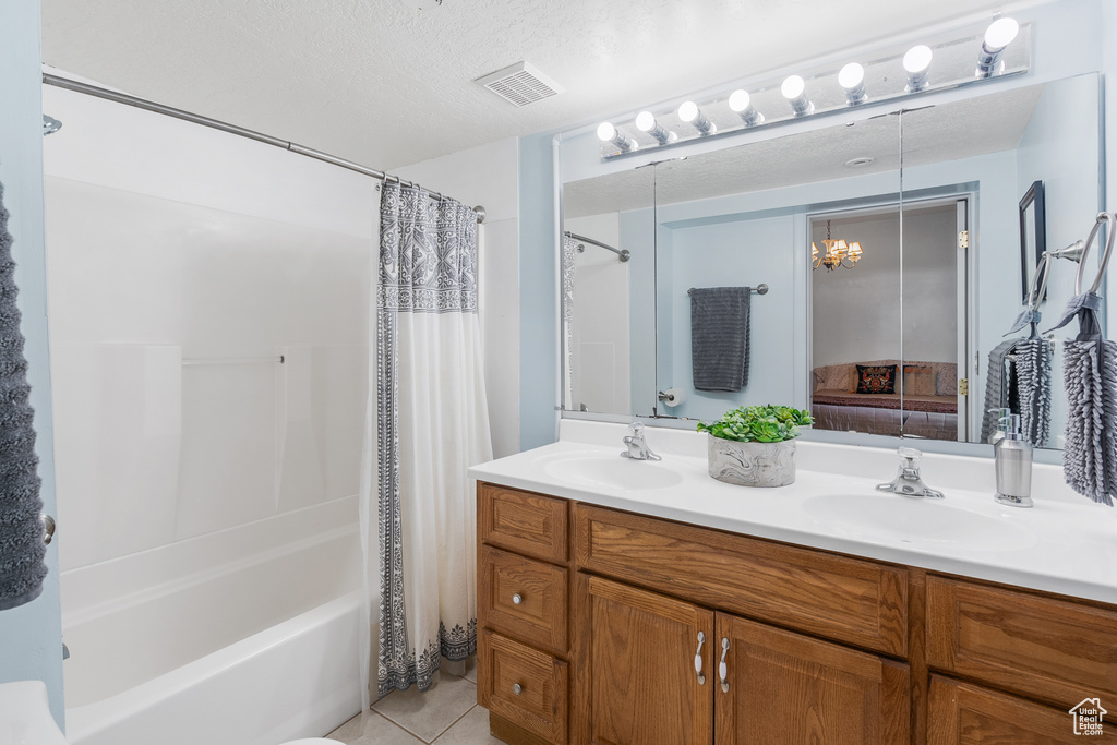 Full bath with double vanity, shower / bath combination with curtain, tile patterned floors, and a textured ceiling