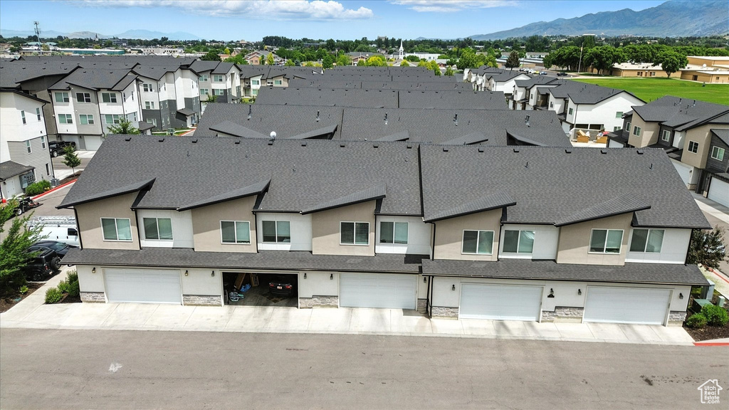 Exterior space featuring stone siding, a garage, a residential view, and a mountain view