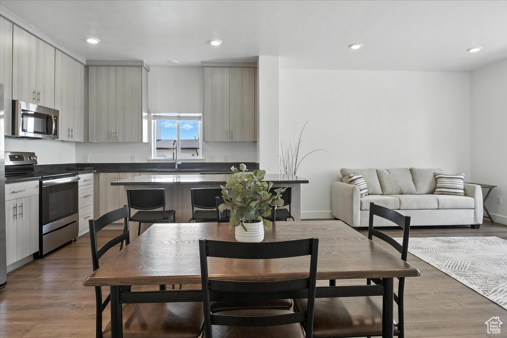 Kitchen with appliances with stainless steel finishes, dark countertops, wood finished floors, and recessed lighting