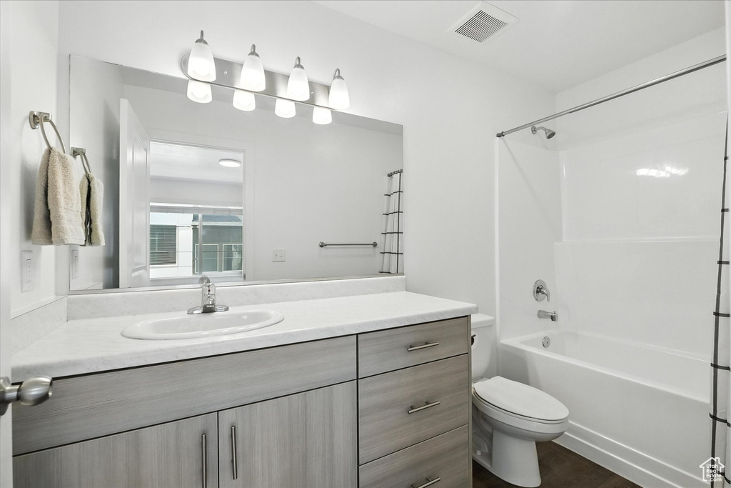 Full bath featuring vanity, washtub / shower combination, and wood finished floors