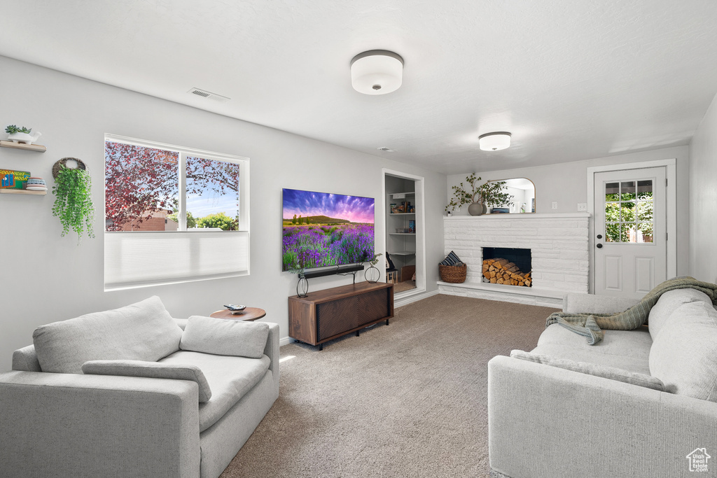 Carpeted living area featuring a fireplace with raised hearth and built in features