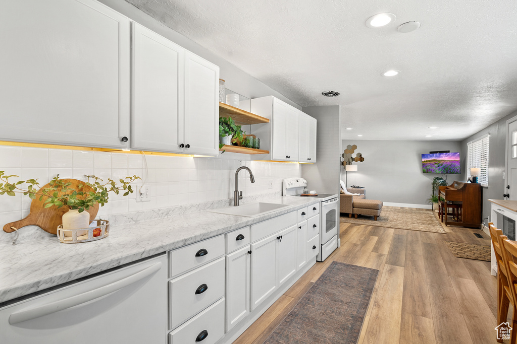Kitchen with white appliances, open shelves, light wood-style flooring, white cabinetry, and recessed lighting