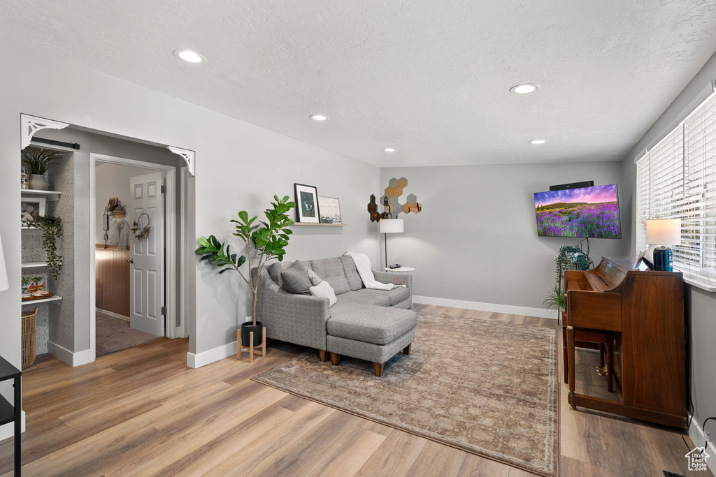 Living area with light wood finished floors, recessed lighting, and a textured ceiling