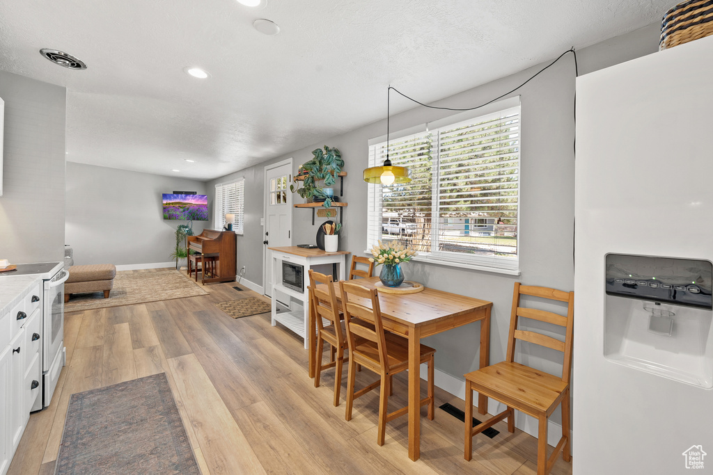 Dining room with light wood-type flooring and recessed lighting