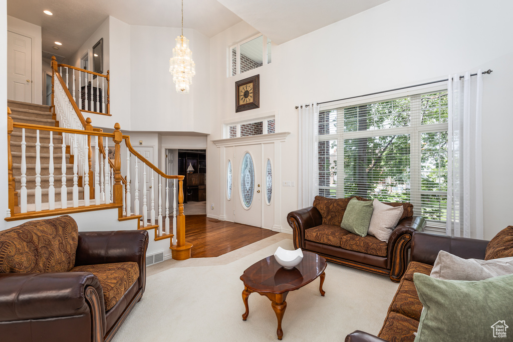 Living room with a chandelier, plenty of natural light, stairway, carpet floors, and recessed lighting