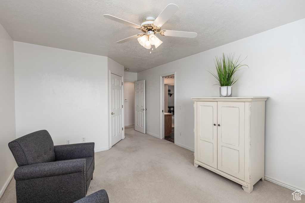 Living area with light colored carpet, ceiling fan, and a textured ceiling