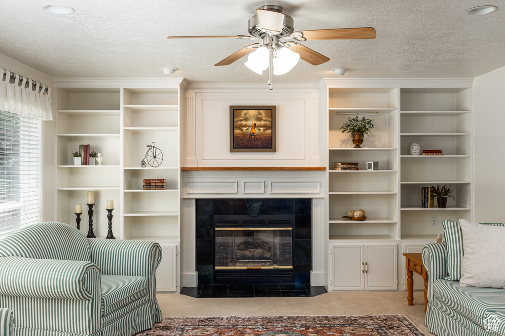 Living room featuring light carpet, ceiling fan, a tile fireplace, and a textured ceiling