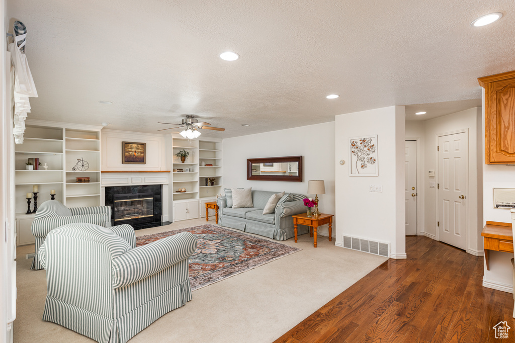 Living area with a ceiling fan, recessed lighting, a fireplace, a textured ceiling, and wood finished floors