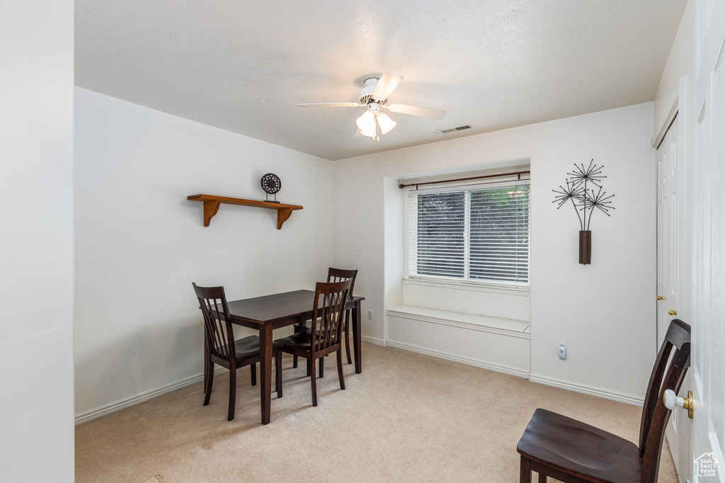 Dining area featuring a ceiling fan and light carpet