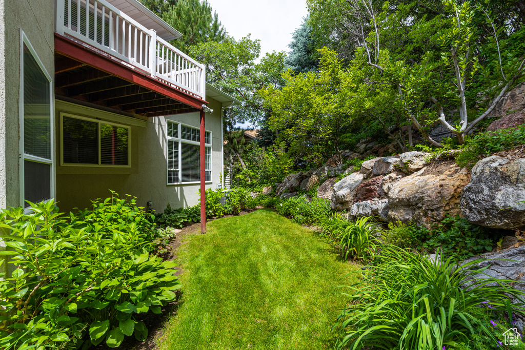 View of green lawn featuring a wooden deck