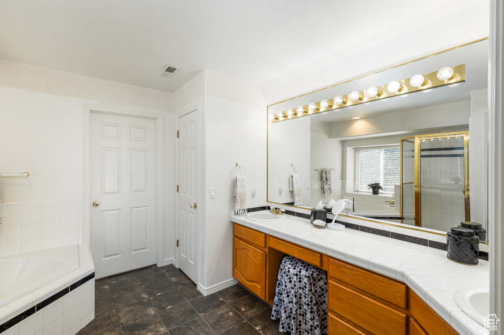 Bathroom featuring double vanity, a bath, and an enclosed shower