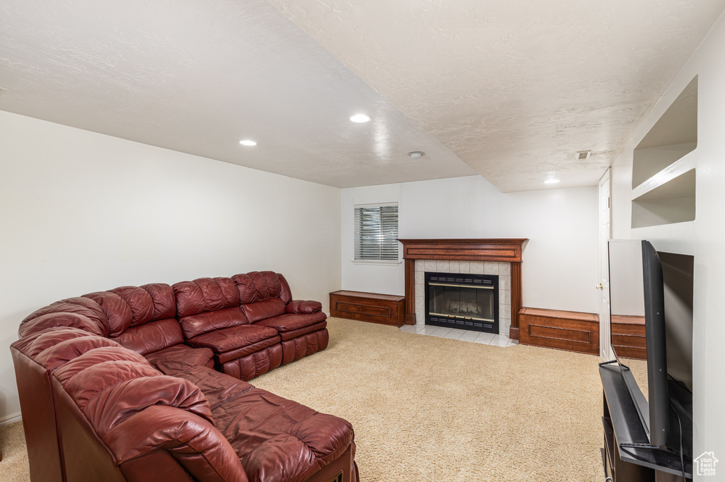 Living room with carpet flooring, recessed lighting, and a tiled fireplace