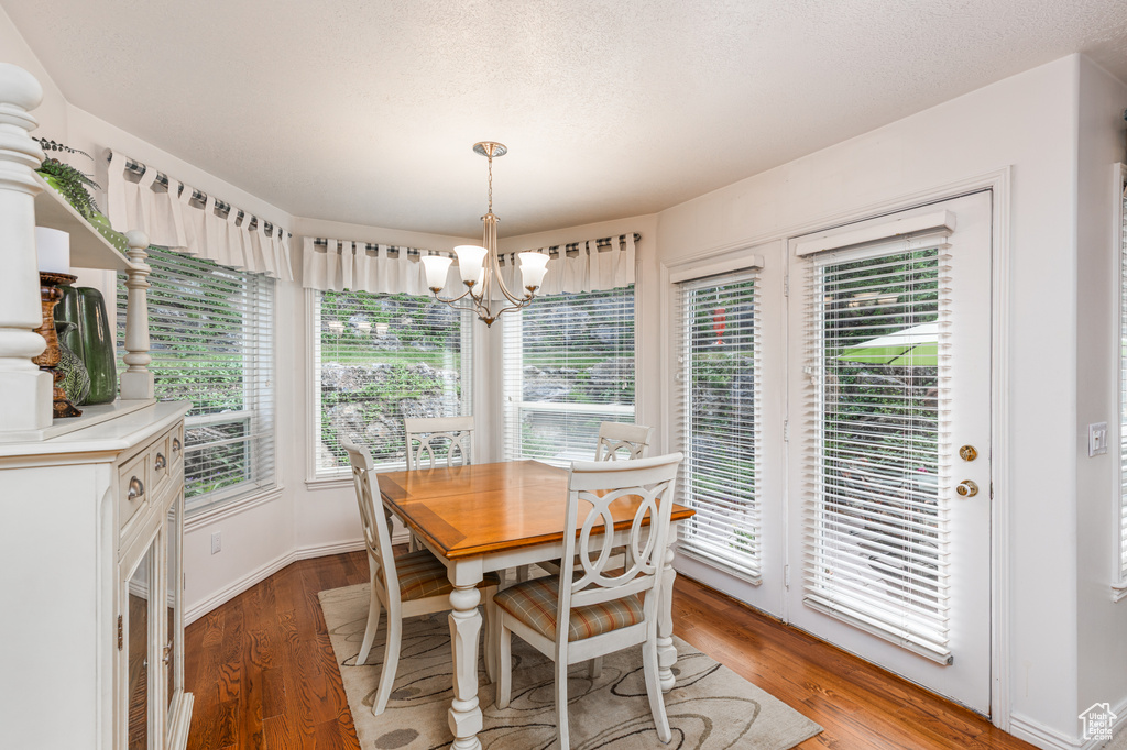 Dining space with a chandelier, light wood-type flooring, and a textured ceiling