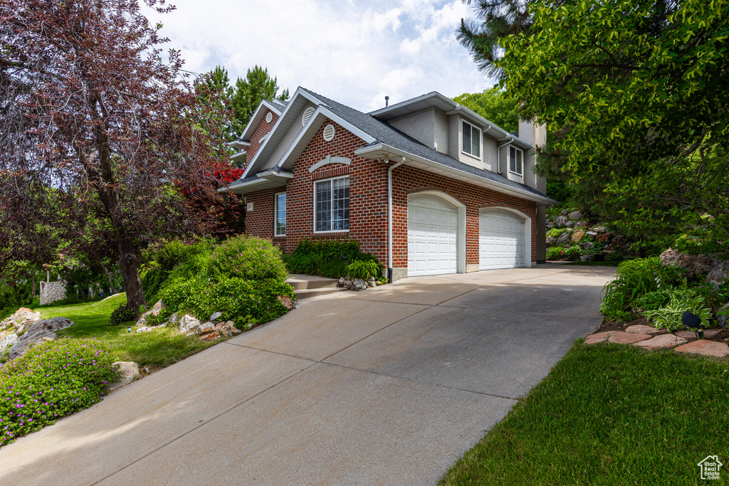 View of front facade featuring brick siding, concrete driveway, and roof with shingles