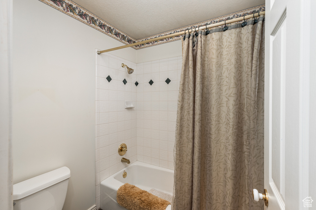 Full bath featuring shower / bath combo with shower curtain and a textured ceiling