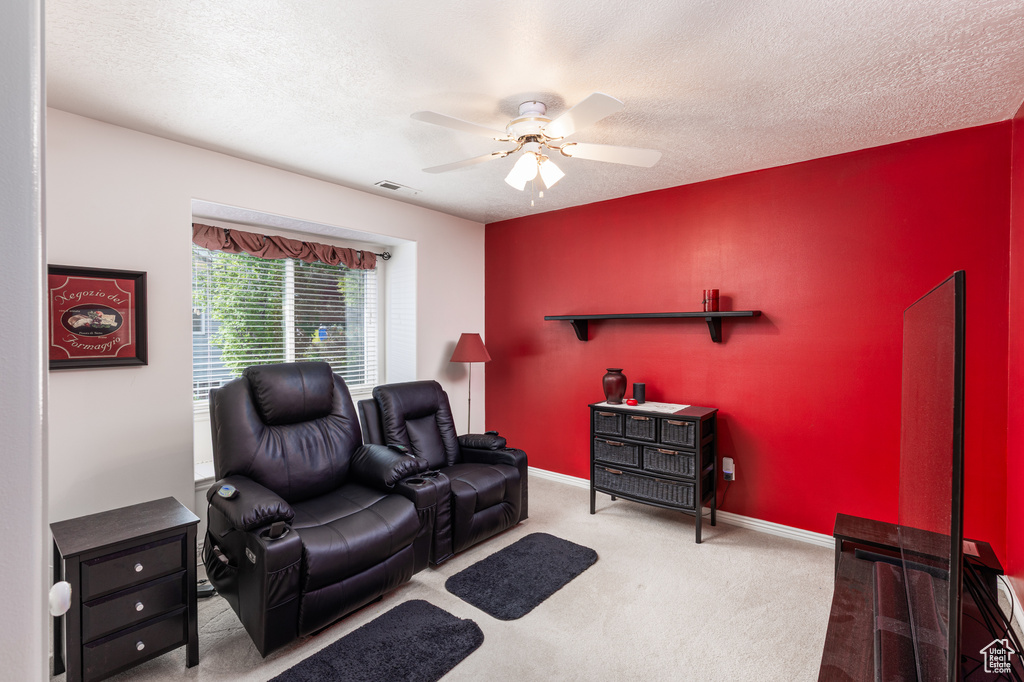 Carpeted living room featuring a ceiling fan and a textured ceiling
