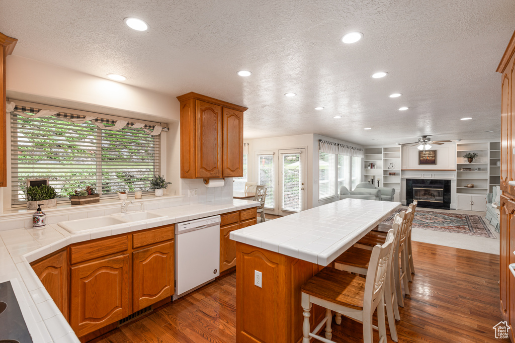 Kitchen with dishwasher, a textured ceiling, recessed lighting, plenty of natural light, and a center island