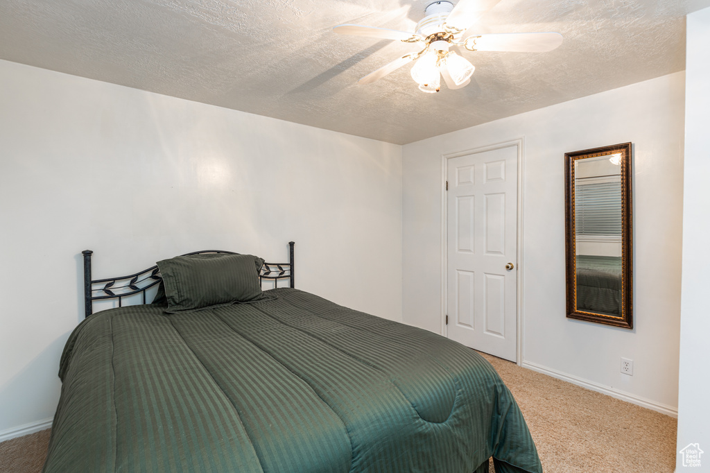 Bedroom featuring carpet, a textured ceiling, and a ceiling fan