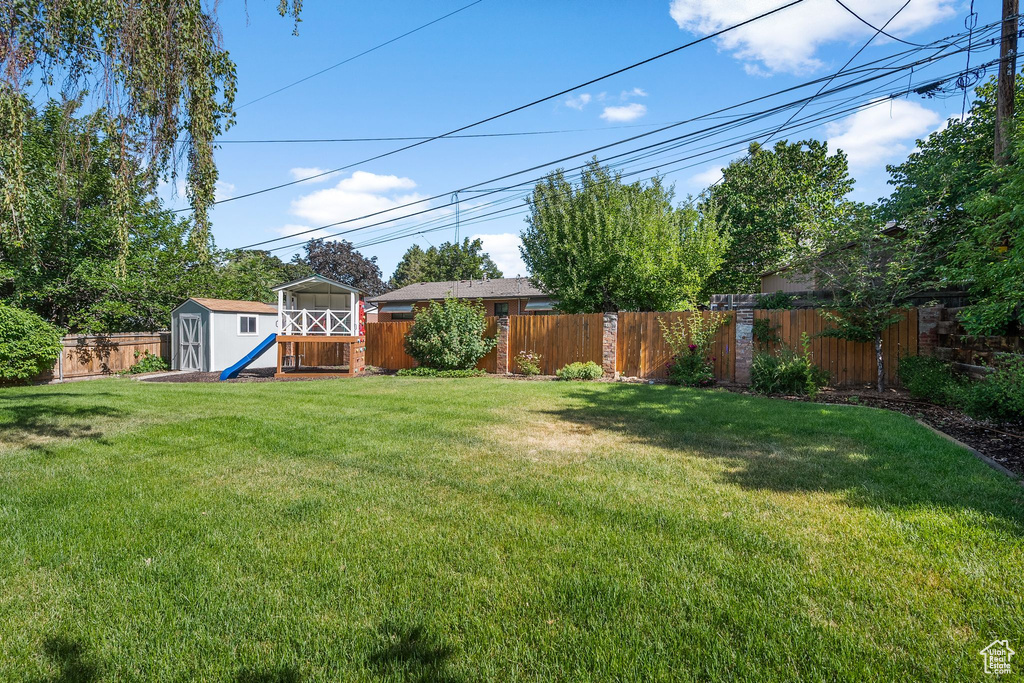 Fenced backyard featuring a storage unit