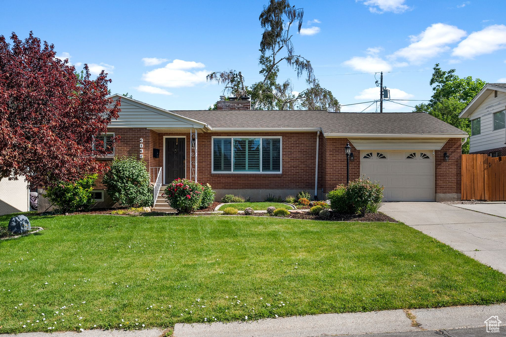 View of front facade with a garage, brick siding, and driveway