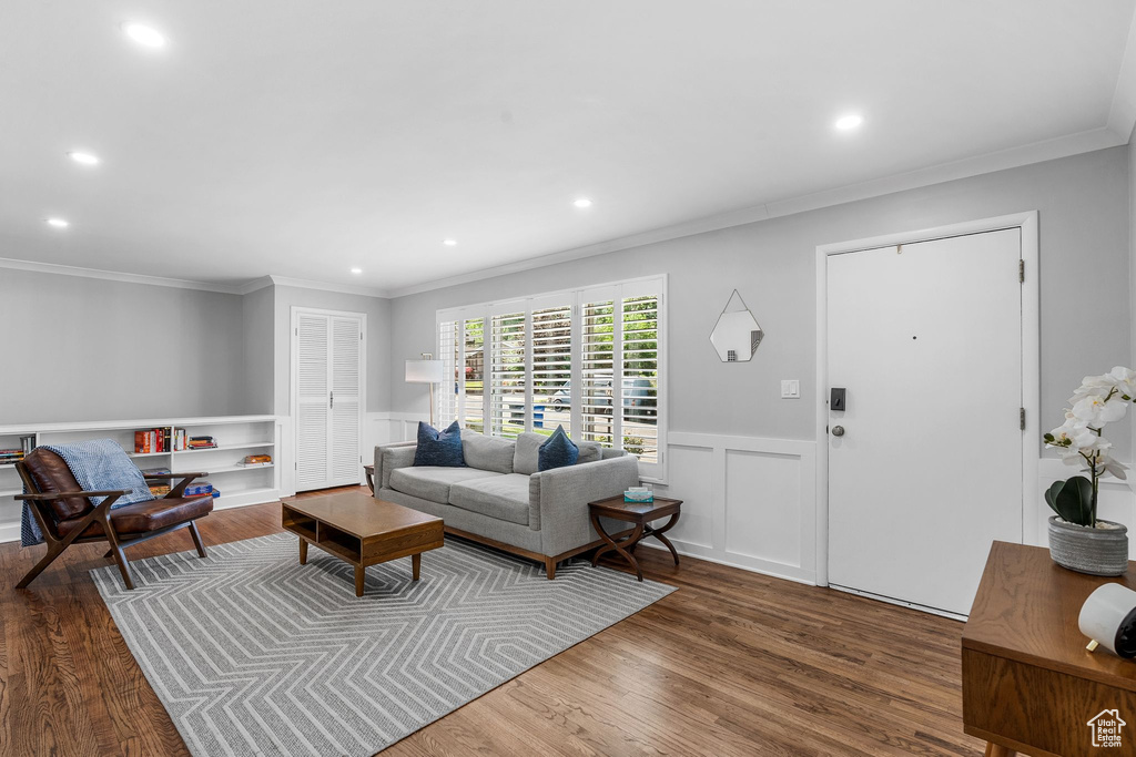 Living room with recessed lighting, wood finished floors, ornamental molding, a wainscoted wall, and a decorative wall