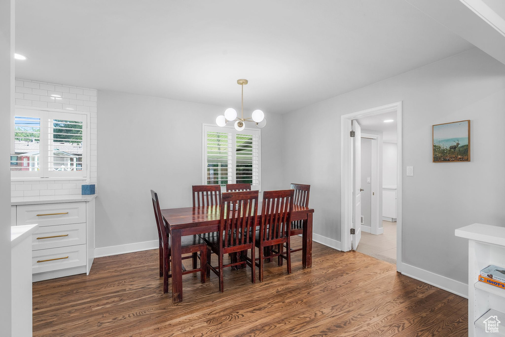 Dining room with dark wood-type flooring, healthy amount of natural light, a chandelier, and recessed lighting