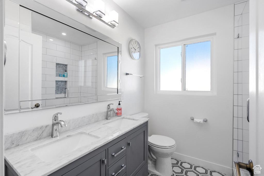 Bathroom with double vanity, a shower, and tile patterned flooring
