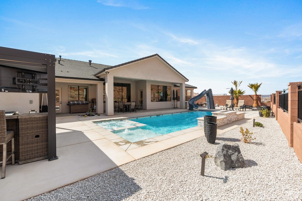 View of pool featuring a water slide, a patio area, and a fenced backyard