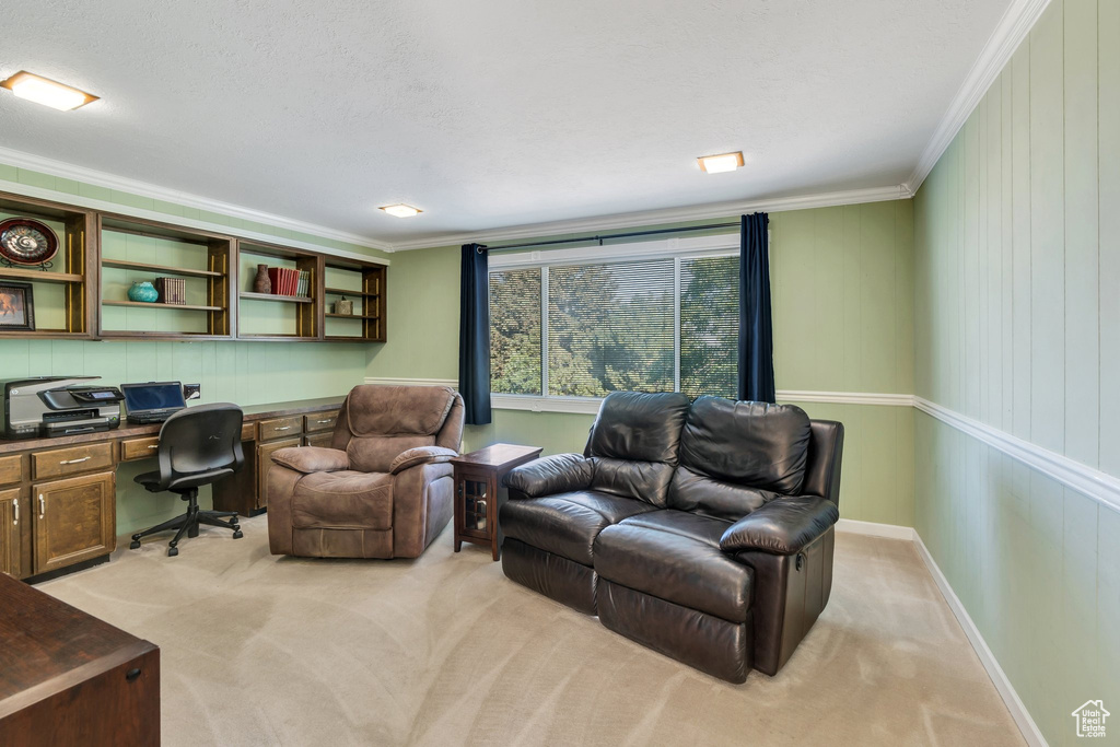 Office space with built in desk, crown molding, and light colored carpet