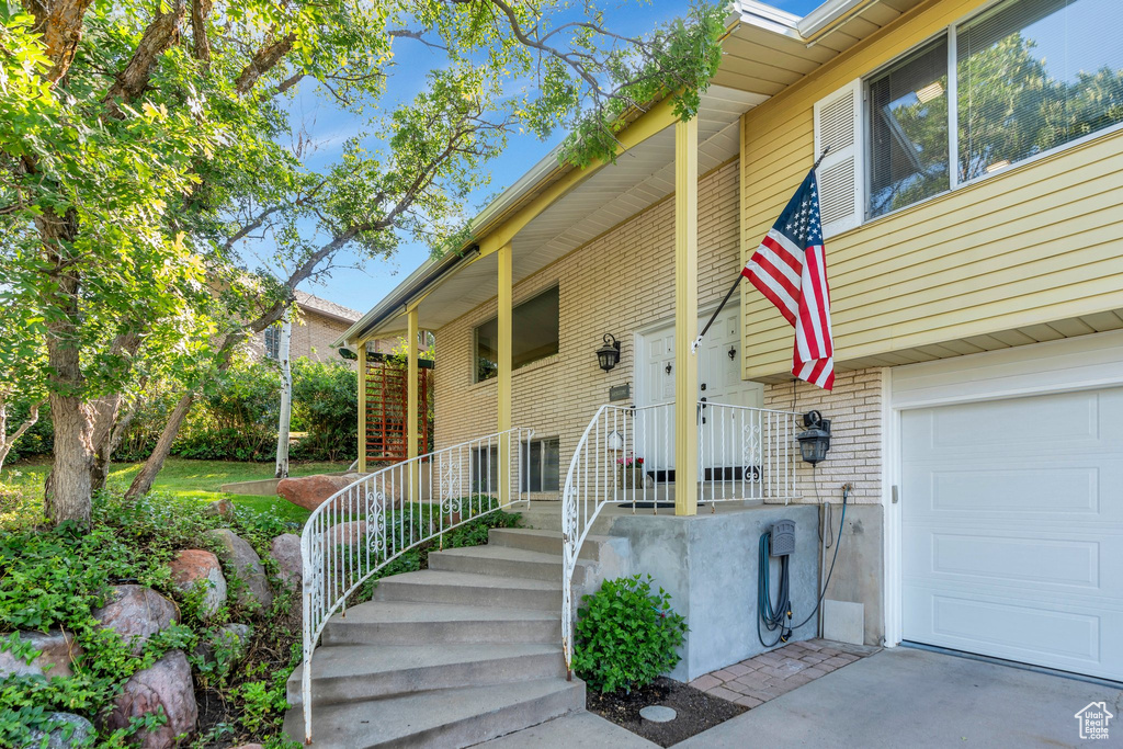 View of exterior entry featuring an attached garage and brick siding