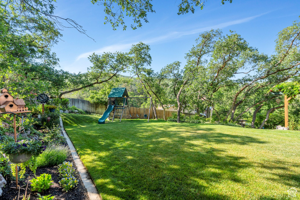 Fenced backyard featuring a playground