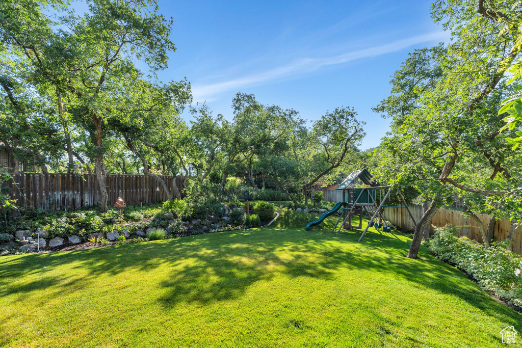 Fenced backyard featuring a playground