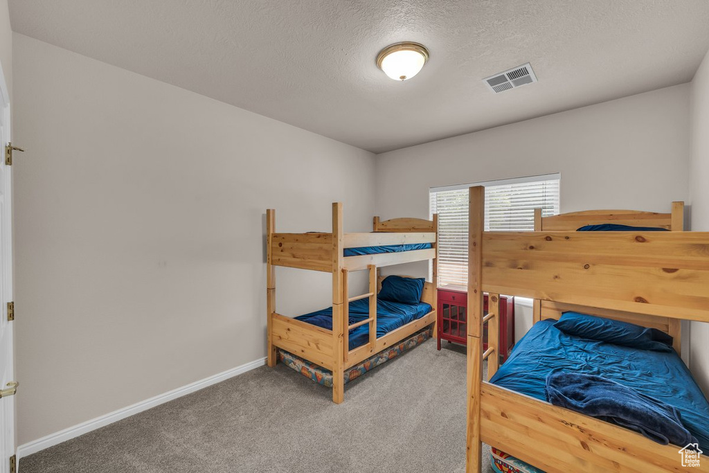 Carpeted bedroom with baseboards and a textured ceiling