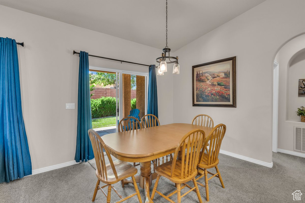 Dining space featuring arched walkways, carpet flooring, and vaulted ceiling