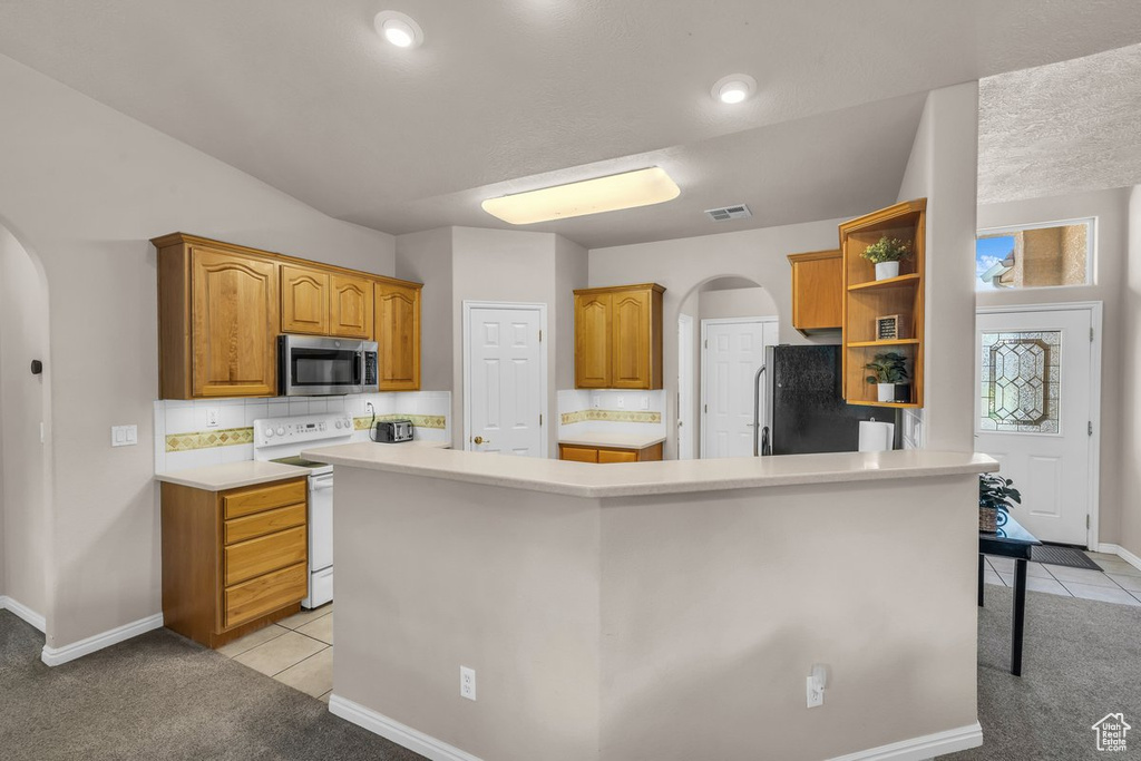 Kitchen featuring stainless steel appliances, arched walkways, open shelves, and light tile patterned floors