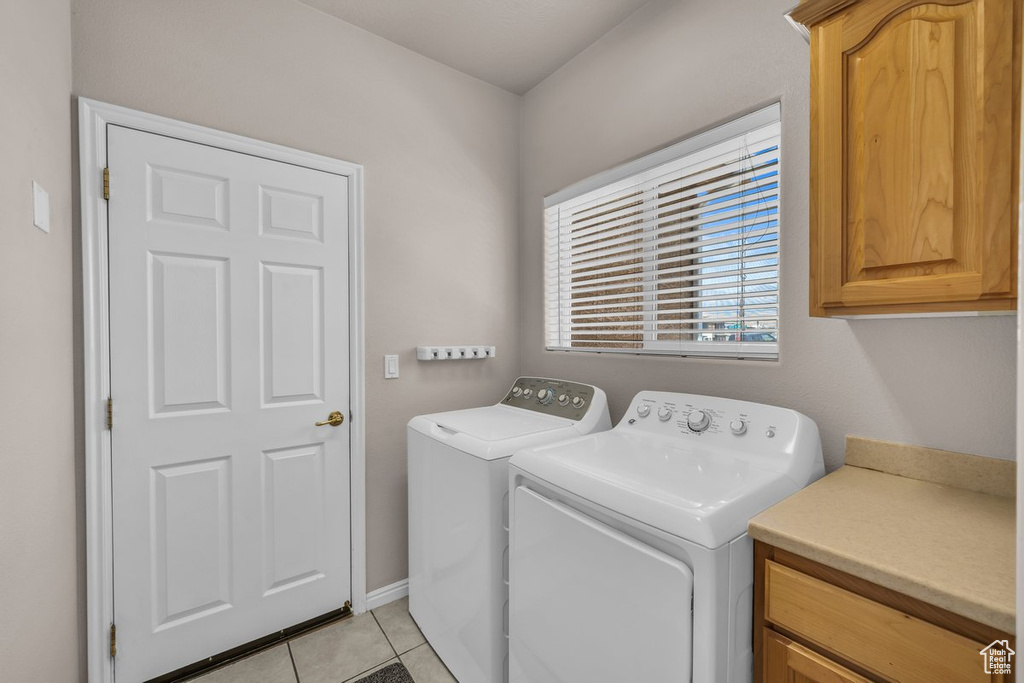 Laundry area with washer and dryer, cabinet space, and light tile patterned floors