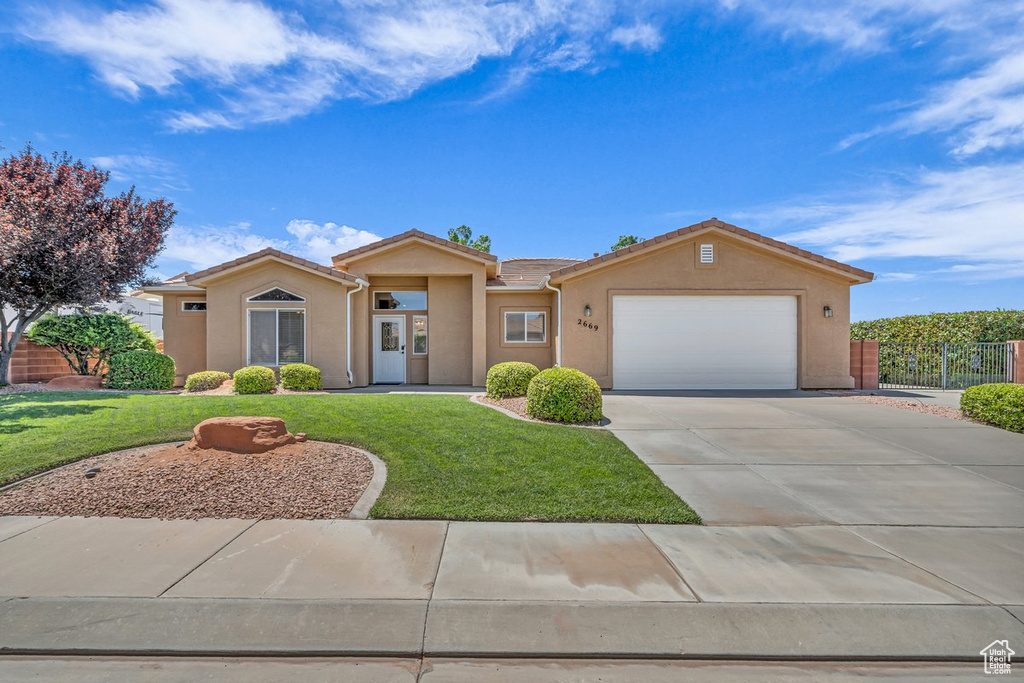 Ranch-style house with stucco siding, an attached garage, driveway, and a tiled roof
