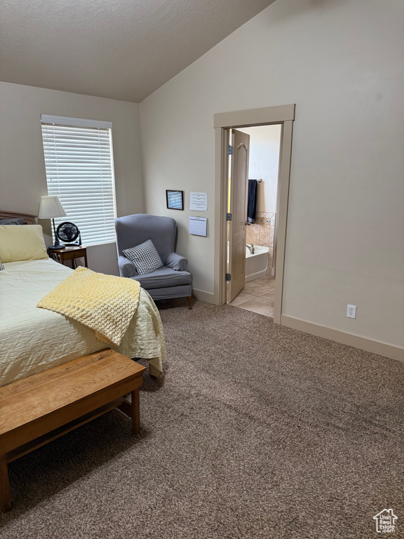 Bedroom featuring vaulted ceiling, light carpet, and ensuite bath