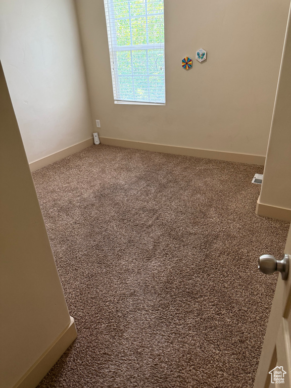 Carpeted spare room featuring baseboards