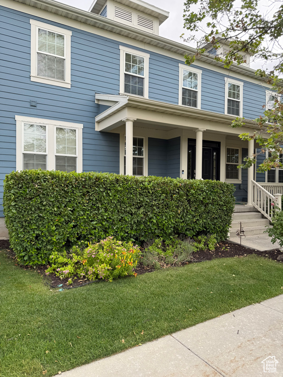 Traditional style home featuring a porch and a front yard