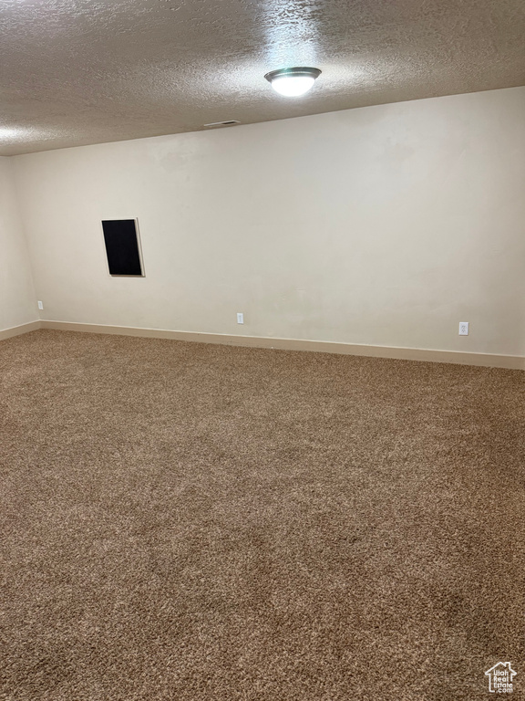 Unfurnished room featuring a textured ceiling and carpet floors