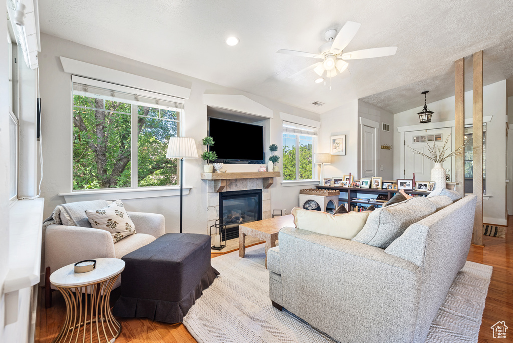 Living room featuring ceiling fan, wood finished floors, a stone fireplace, vaulted ceiling, and recessed lighting