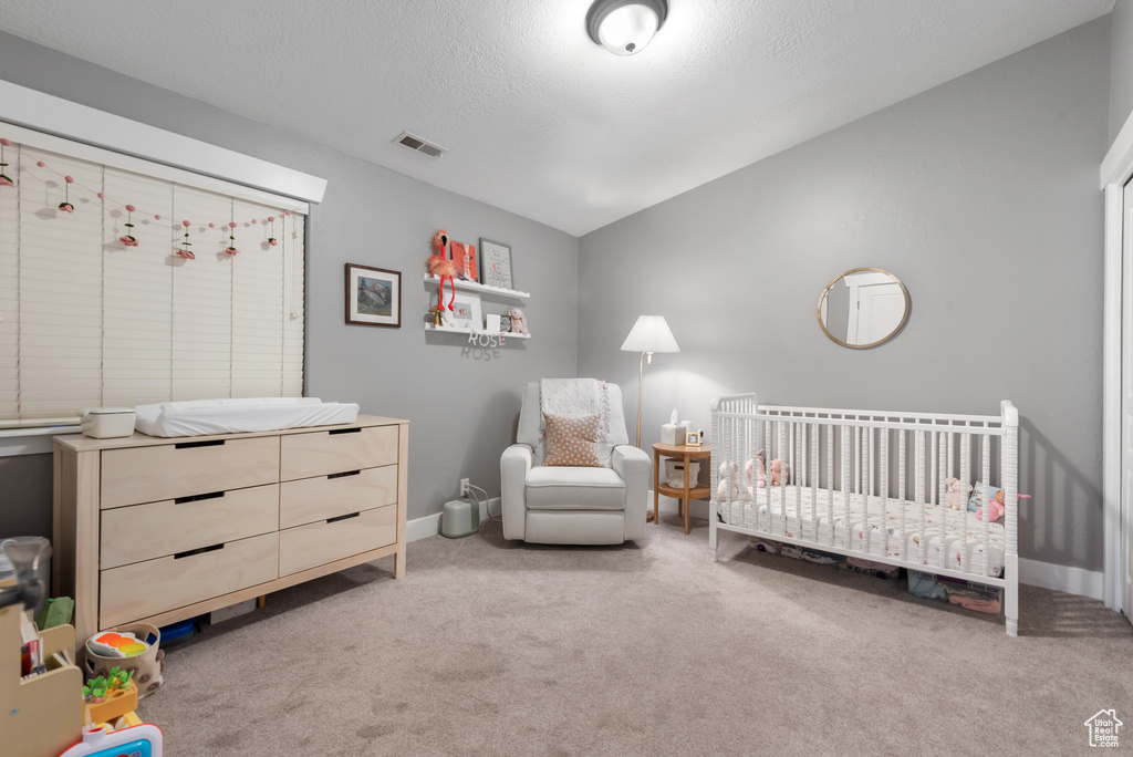 Bedroom featuring light colored carpet and a crib