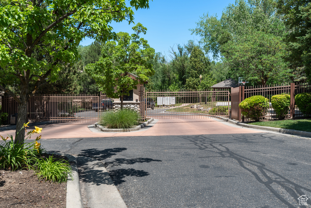 View of asphalt street with curbs, a gate, and a gated entry