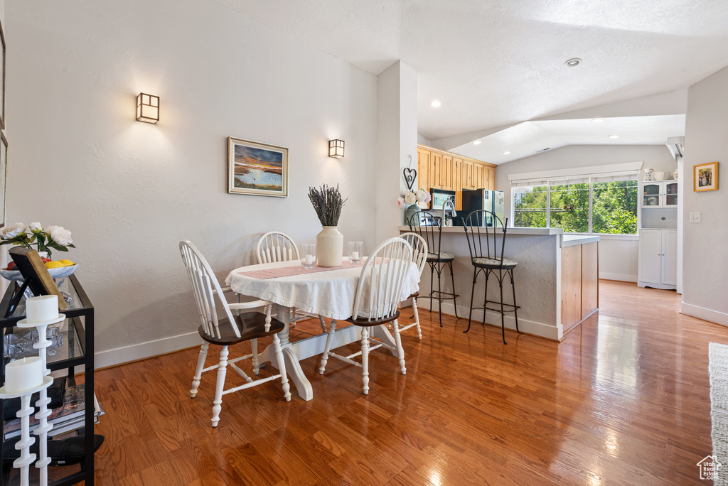 Dining space with lofted ceiling, light wood-type flooring, and recessed lighting