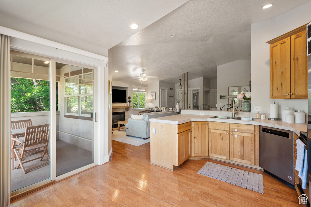 Kitchen with dishwasher, open floor plan, a peninsula, light wood-style floors, and vaulted ceiling