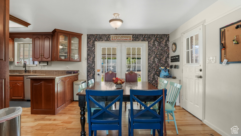 Dining room with light wood finished floors, wallpapered walls, and french doors