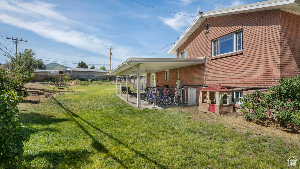 Rear view of property featuring a lawn, brick siding, and a patio