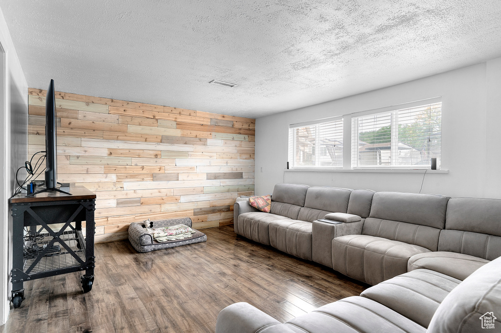 Living area featuring a textured ceiling, wooden walls, and wood finished floors
